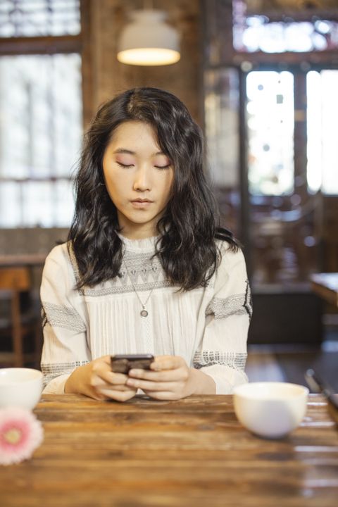 Une jeune femme consulte son téléphone dans un café